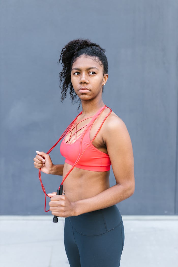 Fit young woman in sports bra with jump rope, embodying fitness and healthy lifestyle.