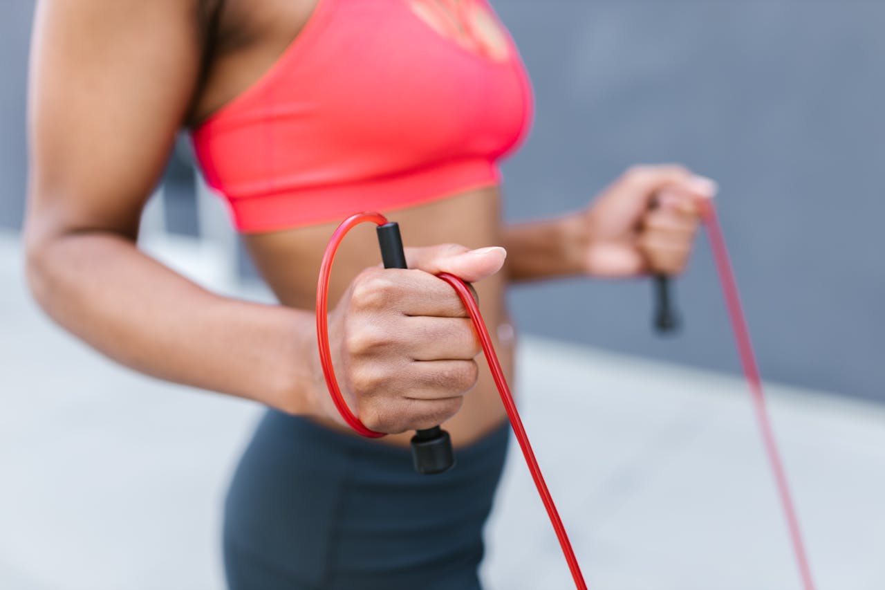 Focused shot of a black woman jump roping outdoors, highlighting fitness and exercise.
